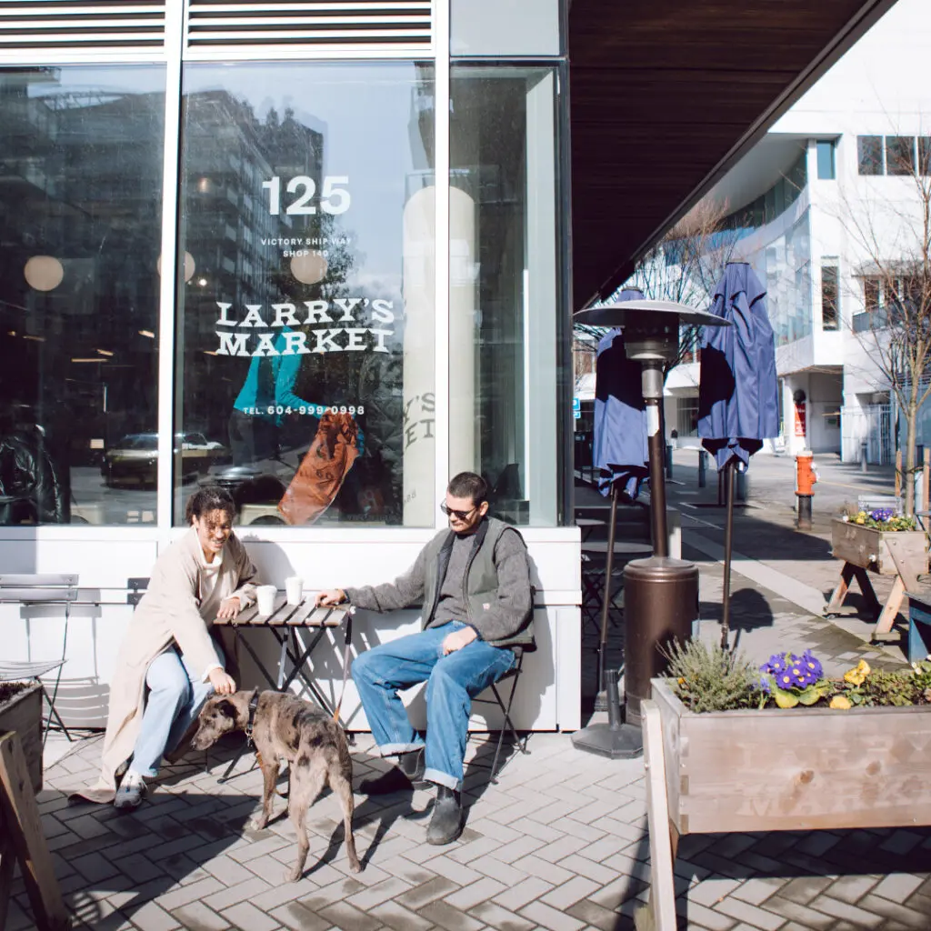 A couple and their dog enjoying coffee outside in Lower Lonsdale, just steps away from Morrison Walk