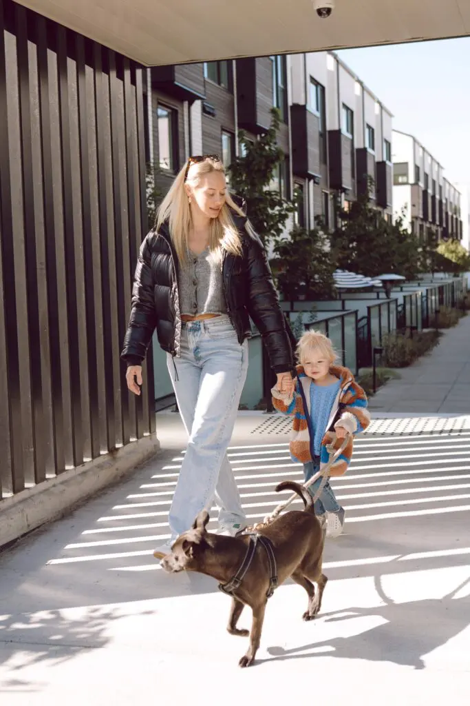 A mom and toddler walking their dog in front of Morrison Walk - Townhomes made for families.